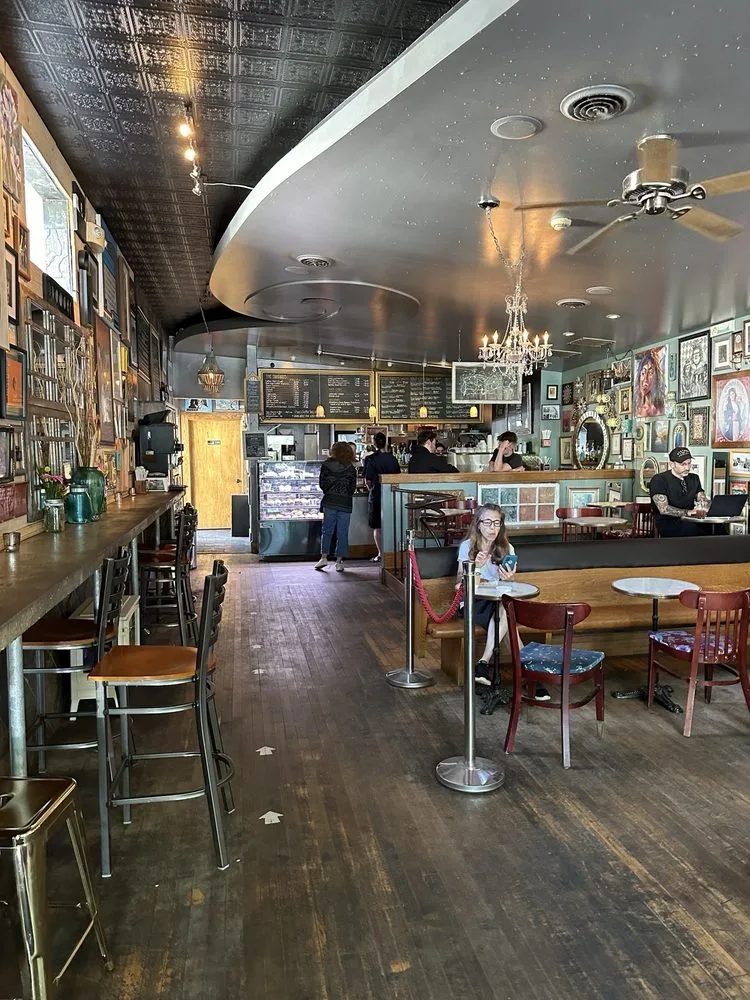 The length of the cafe, with the counter and chalkboard menus on one side and tables down the other